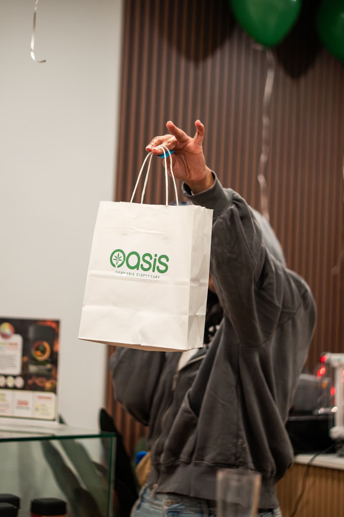 A shopper holding up a white Oasis shopping bag at the counter