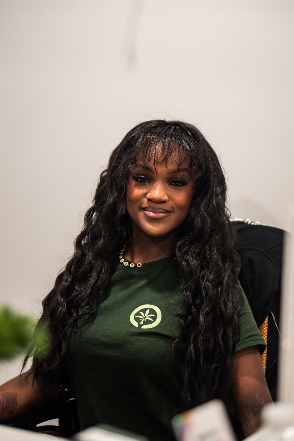 An Oasis team member in a green palm-logo shirt, smiling from behind the counter